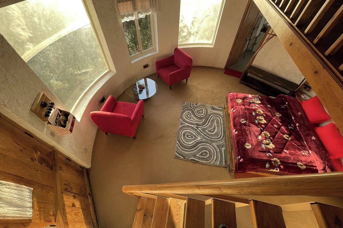 Una habitación con techos altos, un sofá rojo, un tapete estampado y una escalera de madera.