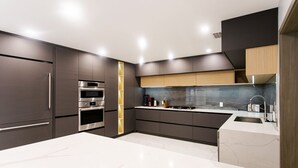 Een moderne keuken met donkere kastjes, een wit aanrecht en roestvrijstalen apparatuur.