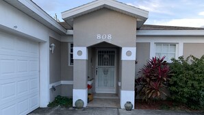 Uma casa residencial com garagem, porta principal e o número '808' exibido acima da entrada.