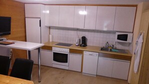 A compact kitchen with white cabinets, a microwave, a coffee maker, and a dishwasher.