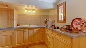 A kitchen with wooden cabinets, a microwave, a sink, and a tray with a mug and a teapot.