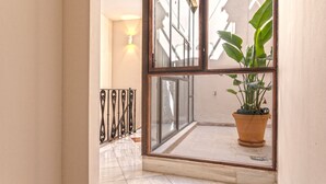 A hallway with a potted plant, a glass door, and a wall-mounted light fixture. - Genteel Home Palacio Abades Terrace III (Sevilla)
