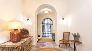 A hallway with a rustic lamp, a wicker chair, and a potted plant on a small table. - Genteel Home Palacio Abades Terrace II (Sevilla)