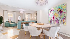 A modern living room with a round dining table, grey upholstered chairs, and a colorful abstract painting on the wall. - Genteel Home Palacio Abades Terrace II (Sevilla)