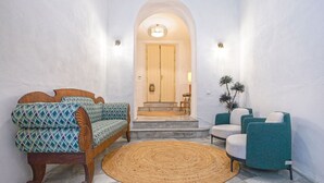A hallway with a wooden bench, a woven rug, and two armchairs. - Genteel Home Palacio Abades Terrace II (Sevilla)