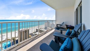 Un balcon avec vue sur la plage et l’océan. On y trouve deux chaises longues et une petite table sur laquelle est posé un plateau avec divers objets.