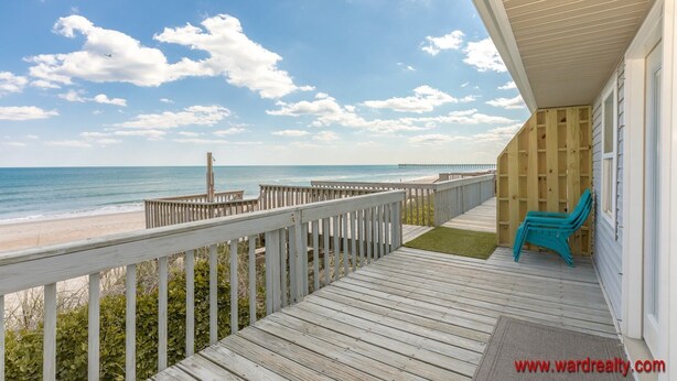 Una terraza de madera con vista a la playa y al océano.