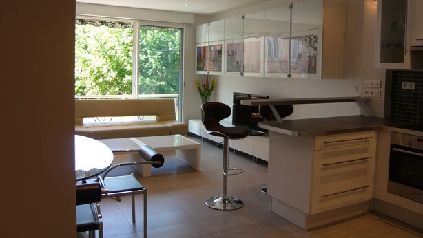 A modern kitchen with white cabinets, a built-in oven, and a dining area with a bench and chairs. - 2 /3 ROOMS NEAR BEACH AND CONVENTION CENTER 4 PEOPLE MAXIMUM (Alpes-Maritimes)