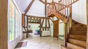 A spacious room with a wooden staircase, large windows, and a tiled floor. - Beautiful cottage with heated swimming pool and large unoverlooked garden (Malleville-sur-le-Bec)