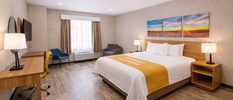 Ein Hotelzimmer mit Bett, Schreibtisch, Stuhl und einem Bild an der Wand.