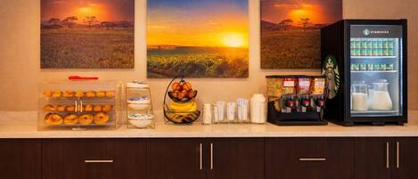 A breakfast bar with pastries, fruit, and a coffee machine.