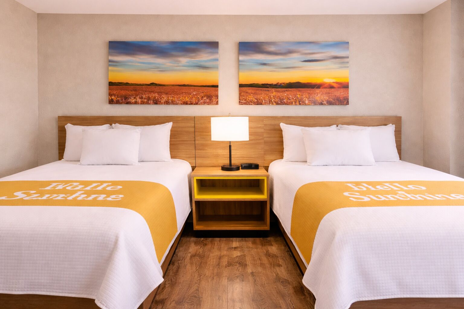 A hotel room with two beds, a nightstand, and two wall-mounted paintings of a sunset over a field.