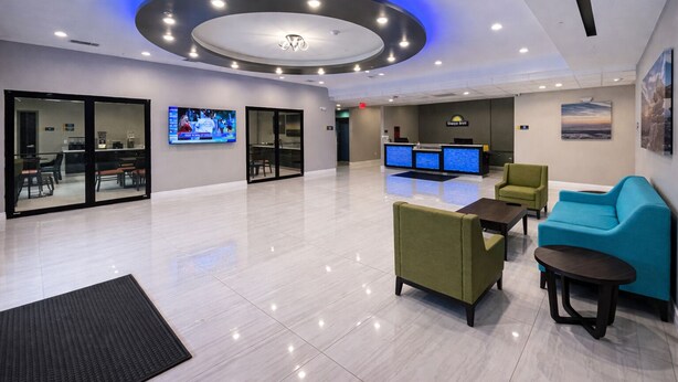 A modern lobby with a reception desk, seating area, and a large screen. - Days Inn & Suites by Wyndham Tomball/Houston NW (Tomball)