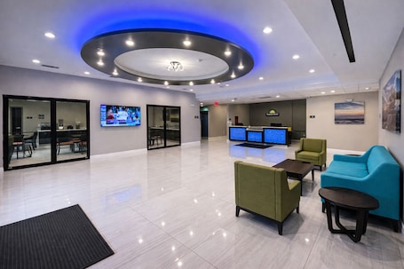 A modern lobby with a reception desk, seating area, and a large screen.