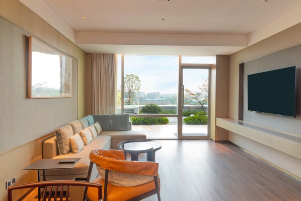 Una sala de estar moderna con un sofá, una mesa de comedor y un televisor montado en la pared.