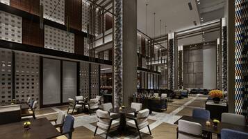 Un lobby de hotel moderno con techos altos, un área de estar central y un bar.