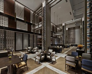 Een moderne hotel lobby met hoge plafonds, een centraal zitgedeelte en een bar.