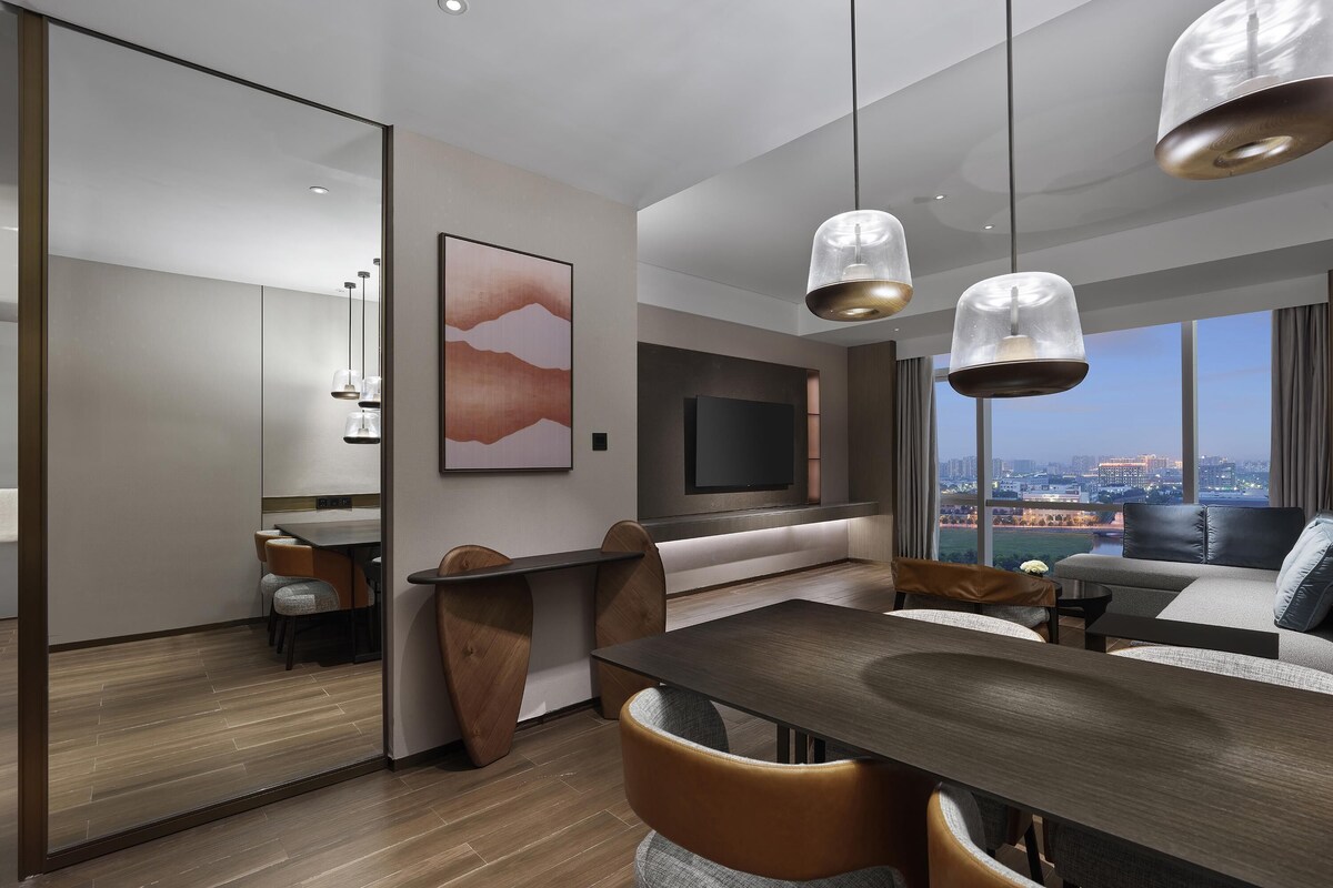 Una sala de estar moderna con comedor, televisor y vista a la ciudad.