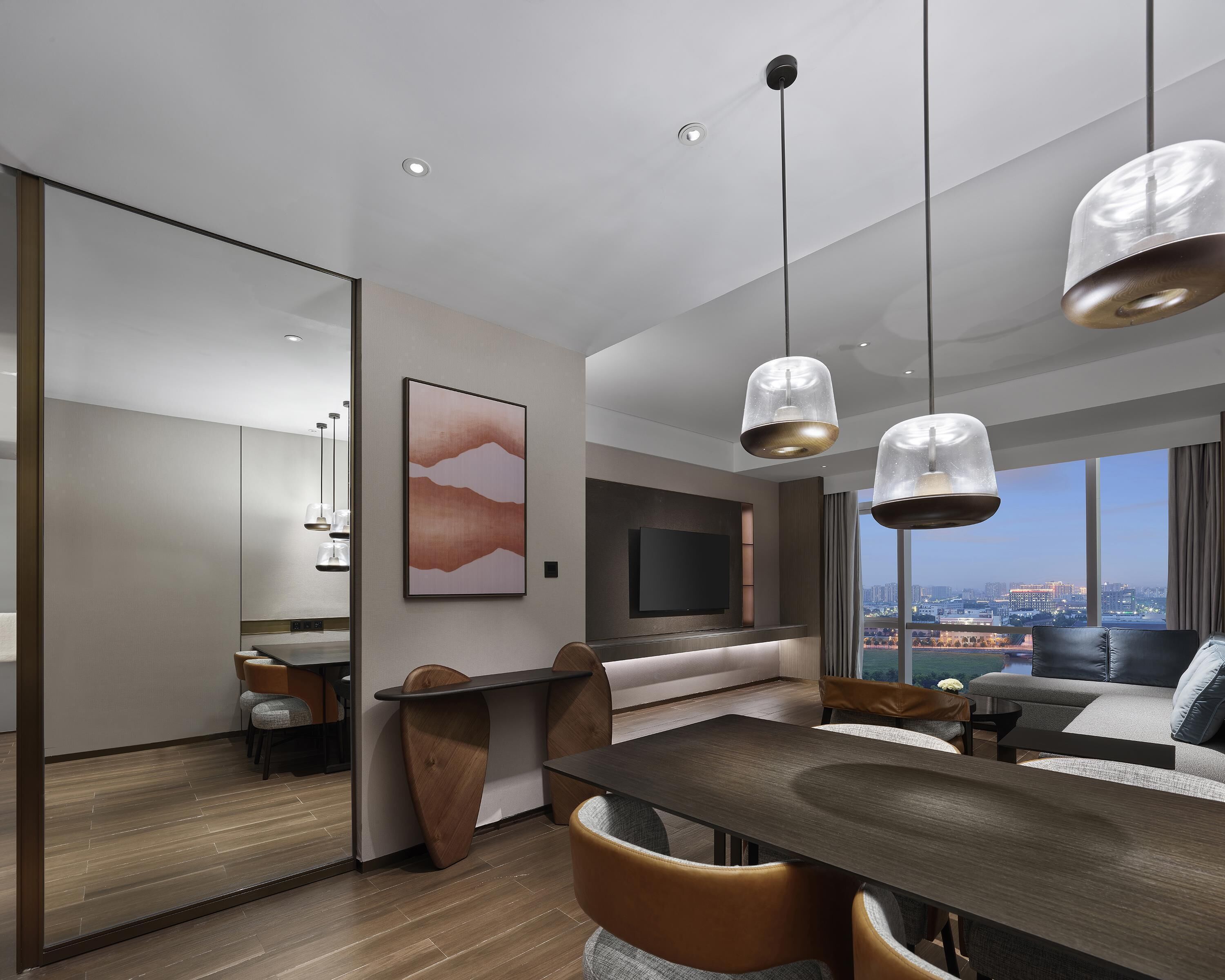 A modern living room with a dining area, a TV, and a city view.