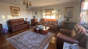 A living room with two brown leather sofas, a coffee table, a patterned rug, and a chandelier. - 2-bed Apartment in High Wycombe Private Garden (High Wycombe)