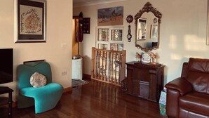 A living room with a teal armchair, a brown leather sofa, a wooden cabinet, and a mirror. - 2-bed Apartment in High Wycombe Private Garden (High Wycombe)