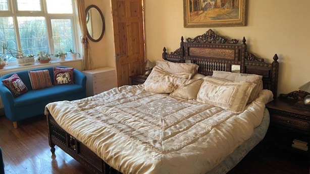 A bedroom with a large bed, a blue sofa, a wooden door, and a painting on the wall. - 2-bed Apartment in High Wycombe Private Garden (High Wycombe)