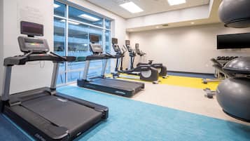 Ein Fitnessraum mit Laufbändern, Crosstrainern und Gymbällen.