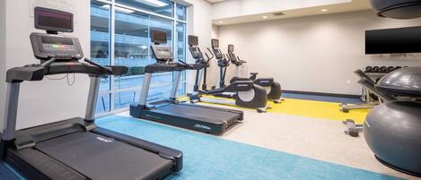 A gym with treadmills, elliptical machines, and exercise balls.