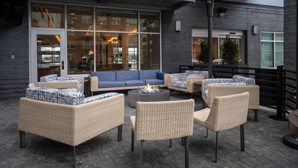 Een terras met wicker meubilair en een vuurkuil.