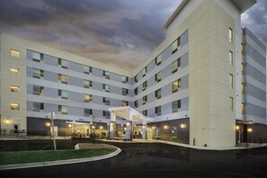 Un hotel de varios pisos con un atrio central, asientos al aire libre y una entrada bien iluminada.