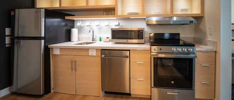 Una cocina moderna con electrodomésticos de acero inoxidable, armarios de madera y un microondas integrado.