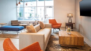 Een moderne woonkamer met een bank, fauteuils, een salontafel en een televisie.