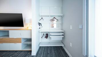 A modern, well-organized room with a flat-screen TV, built-in shelving, and a shoe rack.