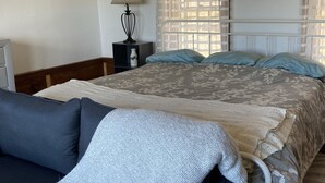 A bedroom with a bed, a nightstand, a lamp, and a window with curtains.