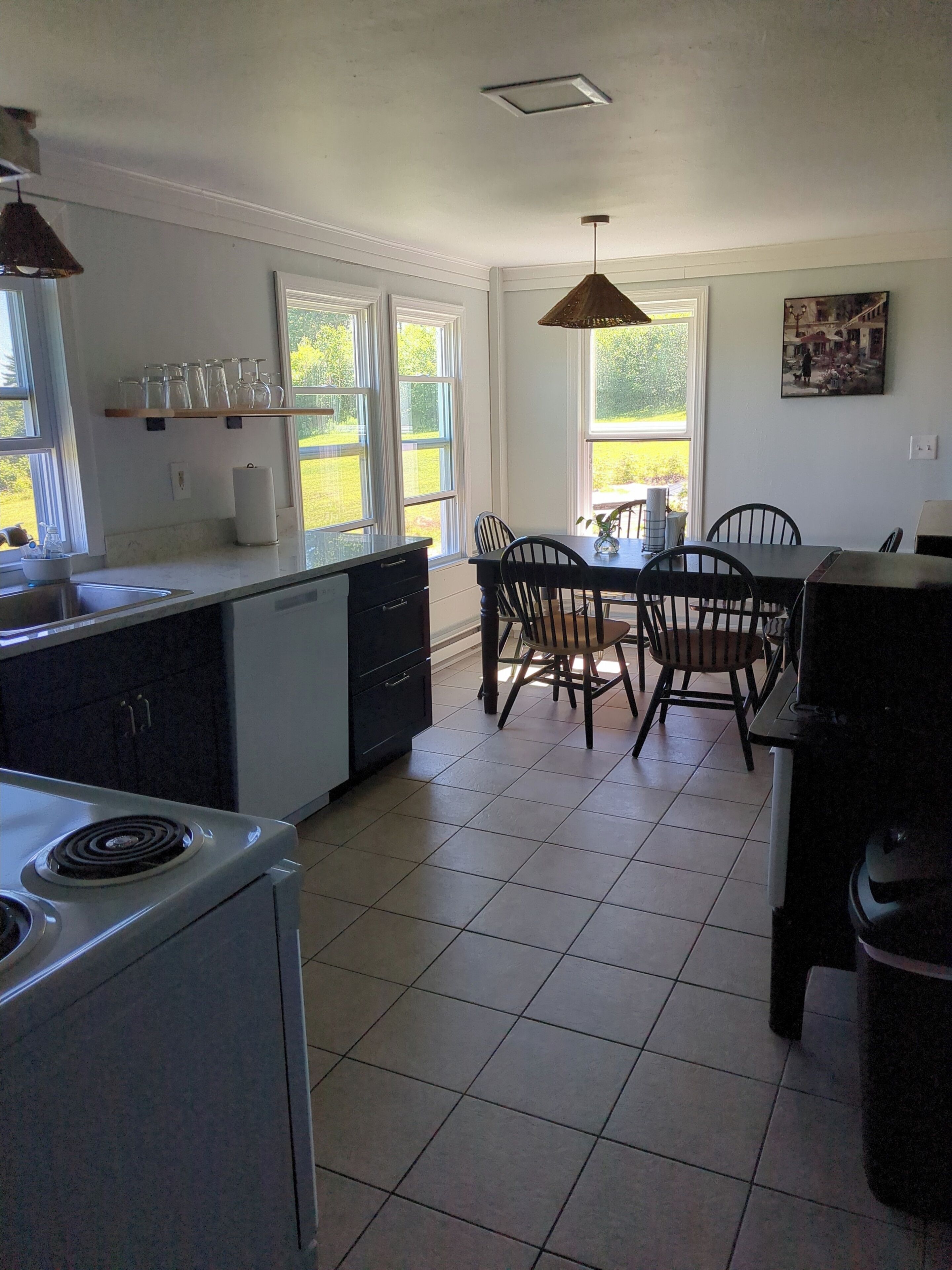 A kitchen with a stove, sink, and dining area with chairs and a table.