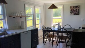 A kitchen with a stove, sink, and dining area with chairs and a table.