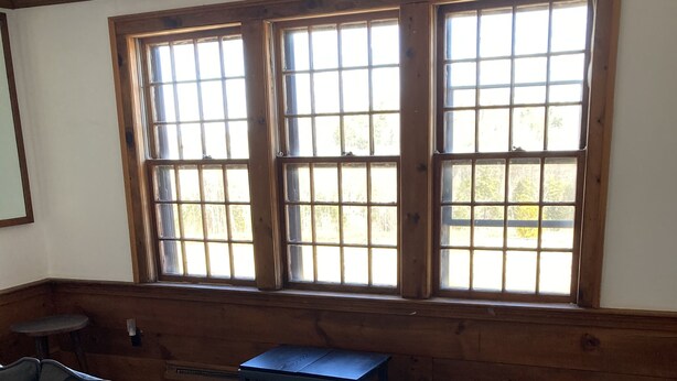 A room with a large window, a sofa, a small table, and a patterned rug.
