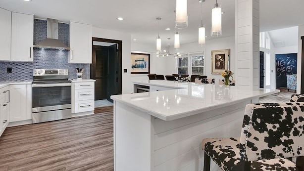 A modern kitchen with white cabinetry, a central island, and pendant lighting.