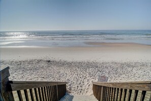 A beach with a wooden fence and a warning sign.