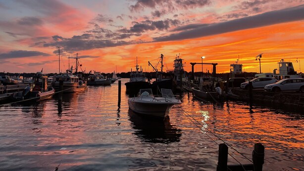 A marina with boats docked at the pier during sunset.