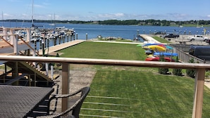 A marina with boats docked, a grassy area with a fence, and a clear view of the water.