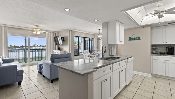 Una cocina moderna con una isla central, armarios blancos y vistas al exterior.