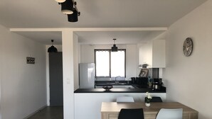 Eine moderne Küche mit Kochinsel, ein Essbereich mit Tisch und Stühlen sowie ein Wohnbereich mit Sofa.