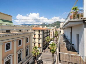 Une vue de rue avec des bâtiments, une terrasse en bois et une montagne en arrière-plan.