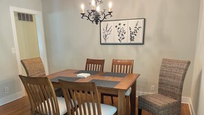 Ein Esszimmer mit Holztisch, vier Stühlen und einer Deckenleuchte.