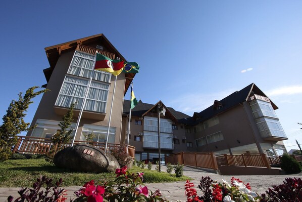 Een hotel met meerdere verdiepingen, balkons, grote ramen en een vlaggenmast met verschillende vlaggen.