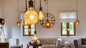 A cozy living room with a large clock on the wall, a sofa, and hanging light fixtures.