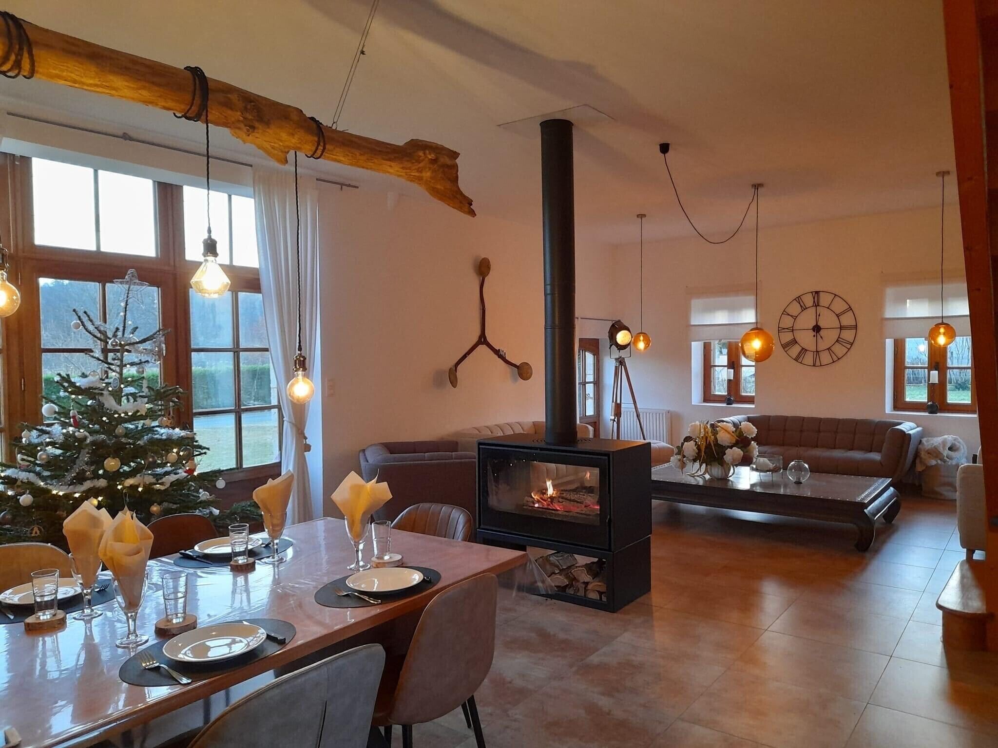 A cozy living room with a fireplace, a dining area set for a meal, and a Christmas tree.