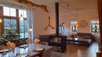A cozy living room with a fireplace, a dining area set for a meal, and a Christmas tree.