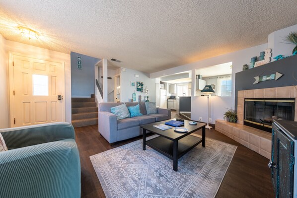A living room with a sofa, coffee table, and fireplace. There is a staircase leading to another room.